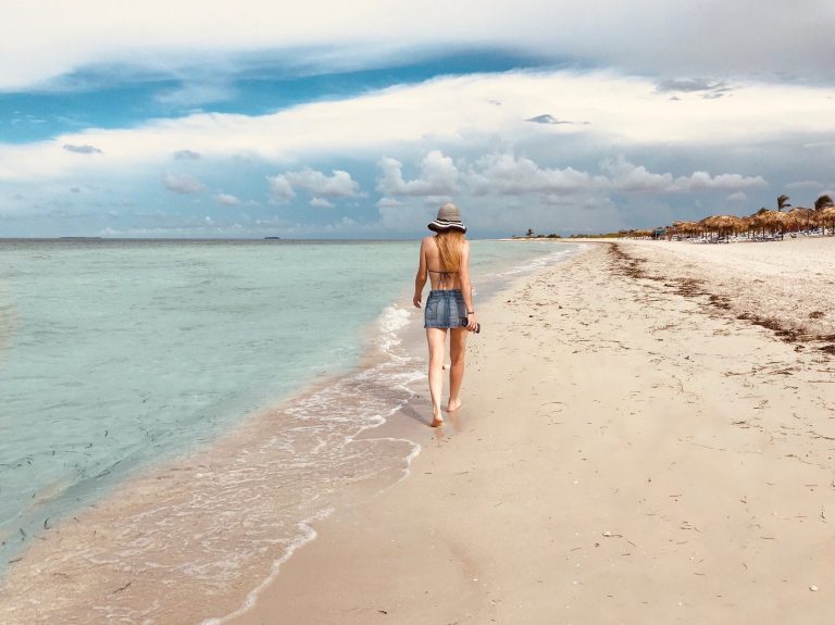 back view photo of women walking by the beach