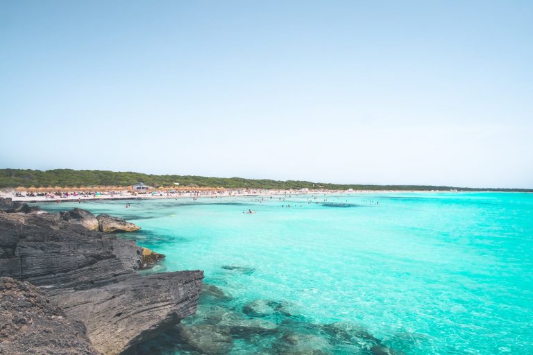 rocky shore beside blue sea water under blue sky