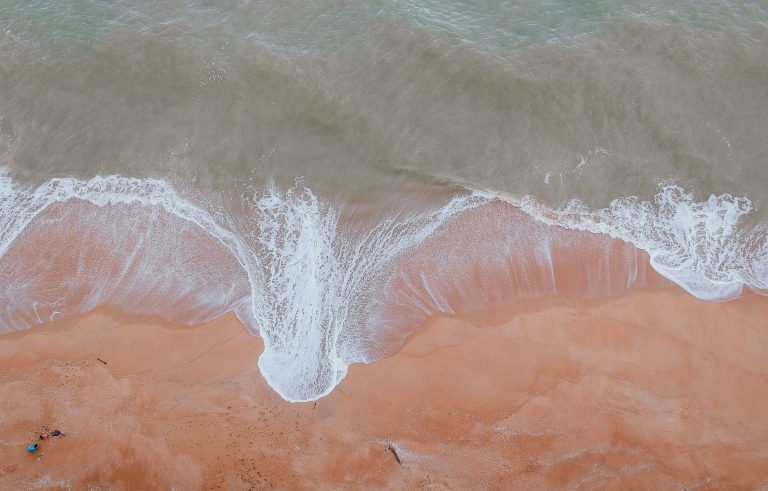 calm body of water beside sand