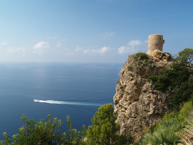 brown rocky mountain beside blue sea under blue sky